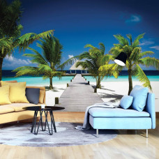 Een fotobehang van de Malediven met palmbomen aan zee, strand en een pier, zichtbaar in een huiskamer.