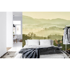 Een sfeervol fotobehang met een nevelig bos en bergen, geschikt voor een slaapkamer.