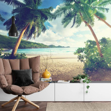 Een fotobehang met palmbomen op een tropisch strand met helder water, afgebeeld in een woonkamer.
