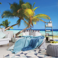 Een fotobehang met palmbomen aan een zonnig strand met zee, zichtbaar in een slaapkamer.