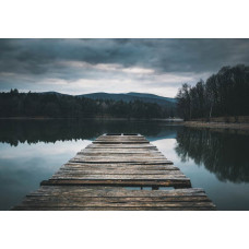Fotobehang van een houten pier die zich uitstrekt over een rustig meer, omgeven door een weelderig natuurlandschap.