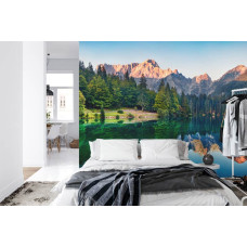 Een fotobehang met een reflecterend meer tussen bergen, weergegeven in een slaapkamer.