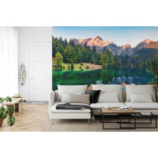 Een fotobehang met een reflecterend bergmeer omringd door bossen en bergen, afgebeeld in een woonkamer.