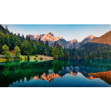 Reflecterend bergmeer met bossen en bergen die in het heldere water weerspiegelen, afgebeeld op een natuurgetrouw fotobehang.