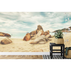 Een fotobehang met een schilderachtig zee- en strandlandschap met rotsen, geschikt voor een slaapkamer.
