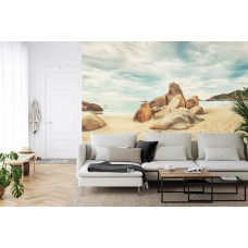 Een fotobehang met een kalm strand met rotsen en zeezicht, perfect voor een woonkamer.