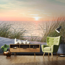 Een fotobehang van een strand en duinen bij zonsondergang aan zee voor de slaapkamer en woonkamer.