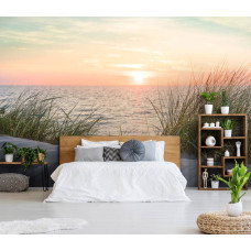 Een fotobehang van een strand en duinen bij zonsondergang aan zee voor de slaapkamer.