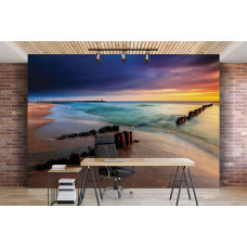 Een fotobehang met uitzicht op een strand bij zonsondergang met een kleurrijke lucht en wolken in een kantoorruimte.