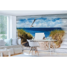 Een fotobehang van een strand met zee en duinen op een achtergrond van houten planken.