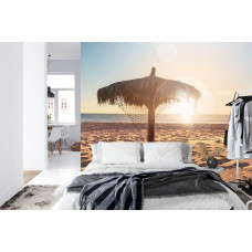 Een fotobehang met een tropisch strand omgeven door een serene zee bij zonsondergang, geschikt voor een slaapkamer.