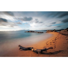 Fotobehang van een time-lapse opname van een strand, waar de oceaangolven het zand overspoelen in een serene setting.