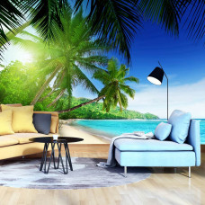 Een fotobehang met een tropisch strand met zon, zee en palmbomen, zichtbaar in een huiskamer.