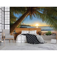 Een moderne slaapkamer met een fotobehang van een tropische setting met een palmboom, een strand, een warme zonsondergang en de stille zee.