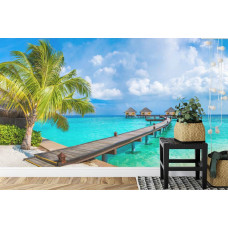 Een fotobehang met een tropische strandscčne met palmbomen en zee in een slaapkamer.