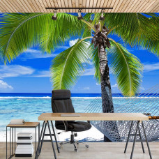 Een fotobehang met een tropisch vakantiebeeld van een palmboom en strand met zee en hangmat, zichtbaar in een kantoor.