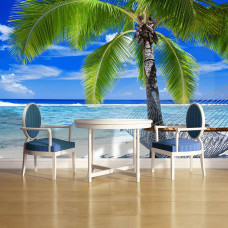 Een fotobehang met een tropisch vakantiebeeld van een palmboom en strand met zee en hangmat, zichtbaar in een keuken.