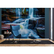 Een zithoek met blauwe fauteuil en voetenbank voor fotobehang van een blauwe waterval.