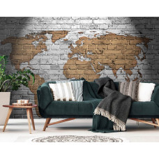 Een fotobehang met een wereldkaart op een stenen muur in goud, grijs en geel tinten.