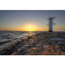 Zee en windmolen bij zonsondergang, weergegeven op een fotobehang met vuurtoren en rotsen.