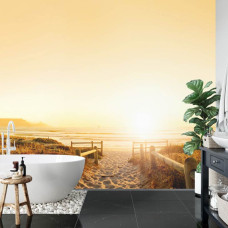 Een fotobehang met de warme gloed van de zon op een strand met duinen en een pad, perfect voor een badkamer.