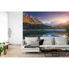 Een fotobehang met een zonsondergang bij een bergmeer, afgebeeld in een huiskamer.