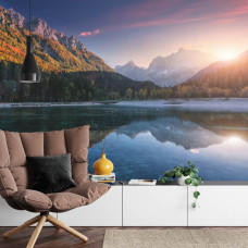 Een fotobehang met een zonsondergang boven een bergmeer, afgebeeld in een woonkamer.