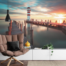 Een fotobehang met een serene zonsondergang bij een vuurtoren en kalme zee, geschikt voor een huiskamer.