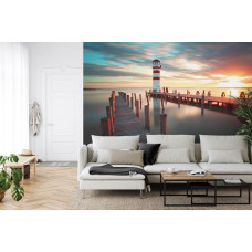 Een fotobehang met een vuurtoren die oplicht bij een warme zonsondergang, ideaal voor een woonkamer.