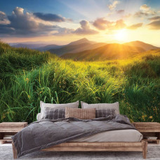 Een fotobehang van een zonsondergang over bergen, ideaal voor een slaapkamer, waarbij de natuur in de achtergrond met zachte kleuren het rustgevende effect versterkt.