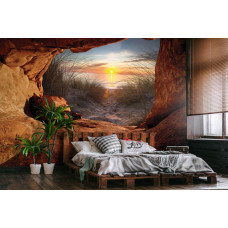 Een fotobehang van een zonsondergang vanuit een grot, met uitzicht op de duinen, zee en strand in vliesbehangstijl voor een slaapkamer.