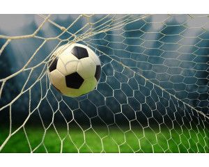 Fotobehang van een voetbal die het doel binnengaat, met een helder zicht op het net tijdens het scoren.