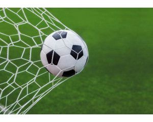 Fotobehang van een voetbal die met kracht in het doel schiet, waarbij het net strak gespannen staat na het doelpunt.