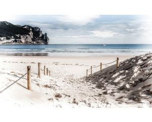 Zandpad op het strand dat leidt naar de kustlijn met de blauwe zee op de achtergrond, fotobehang voor een serene strandwandeling.