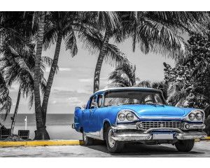 Blauwe klassieke auto op een strand in Cuba, met wuivende palmbomen en de kalme zee op de achtergrond, fotobehang voor een exotische en vintage sfeer.