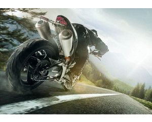 Fotobehang snelle motor in de bergen met een indrukwekkend uitzicht op een lange weg en prachtige bergen.