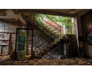 Verlaten trappenhuis in een industrieel gebouw, met een verwaarloosde en mysterieuze uitstraling op dit fotobehang.