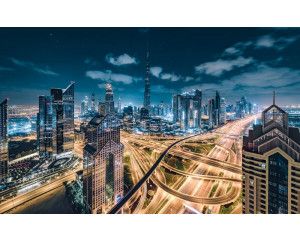Verlichte stad in de nacht met snelwegen door het landschap.