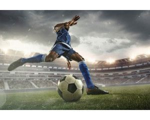 Fotobehang van een voetballer die actief speelt in een groot stadion, vastgelegd tijdens een cruciaal moment in de wedstrijd.