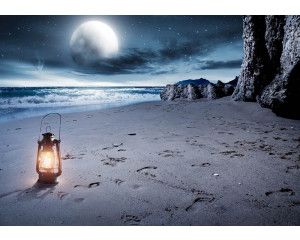 Fotobehang van een volle maan boven een strand en zee, met een sfeervolle lantaarn.