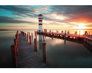 Fotobehang van een zonsondergang bij een vuurtoren aan de kust, met een prachtig uitzicht over de zee en natuur.