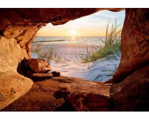Fotobehang van een zonsondergang boven zee, gezien vanuit een grot met duinen en strand.