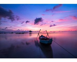 Fotobehang van een zonsondergang over een meer en zee, met landschap, boot en kano.