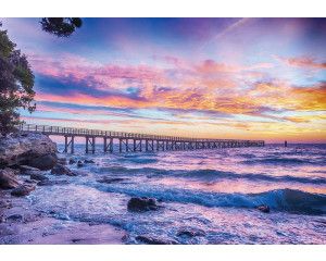 Zonsondergang boven de zee met een pier in de verte, vastgelegd op fotobehang.