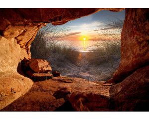 Fotobehang van een zonsondergang serenade, gezien vanuit een grot met uitzicht op de zee en strand.