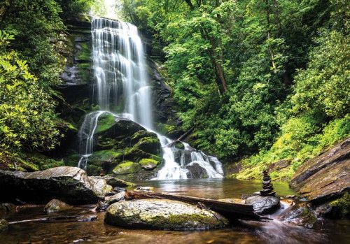 Fotobehang van een betoverende waterval die door een bos stroomt, omringd door dichte bomen en natuur.